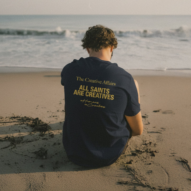 Person sitting on a beach wearing a dark blue shirt with text.